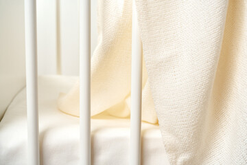 Muslin baby blanket hanging on child's bed in nursing room - obrazy, fototapety, plakaty