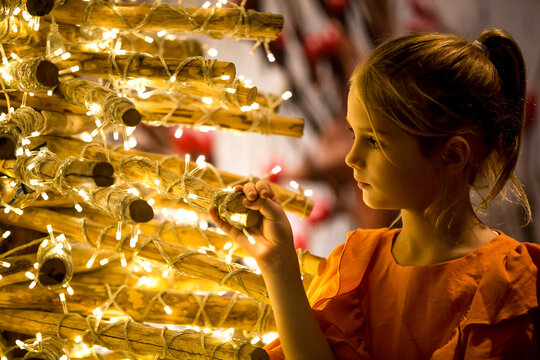 Little girl decorating eco friendly, reusable handmade Christmas tree made of driftwood and branches. Merry Christmas and happy holidays
