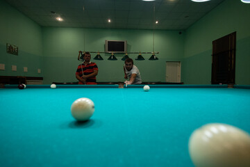 A group of people gathered in the billiard room to play and have fun. A group of friends plays...