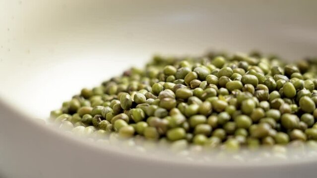 Raw green mung beans in ceramic bowl close up. Rotation