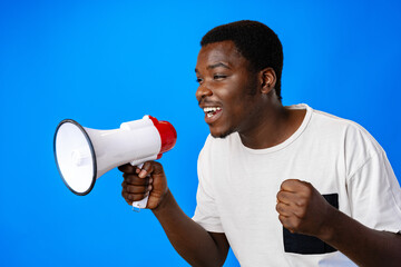Positive african guy shouting with megaphone over blue background