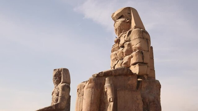 two giant ruined statues of pharoahs at Colossi of Memnon in Luxor, Egypt