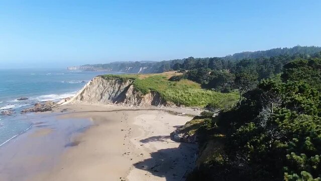 Drone shot revieling the blend of green cliffs, sandy shores, and ocean waves, offering the coastal landscape of Bodega Bay and Gualala Coast in California.
