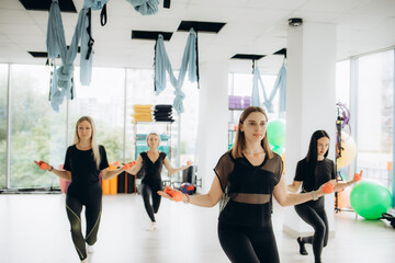 Young happy female athlete warming up with group of women on exercise class at health club.