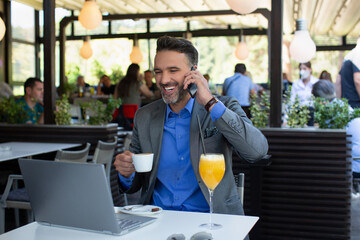Happy businessman in suit talking on the smartphone and laughing in the restaurant