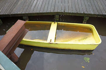 Boat filled with water moored next to a bridge