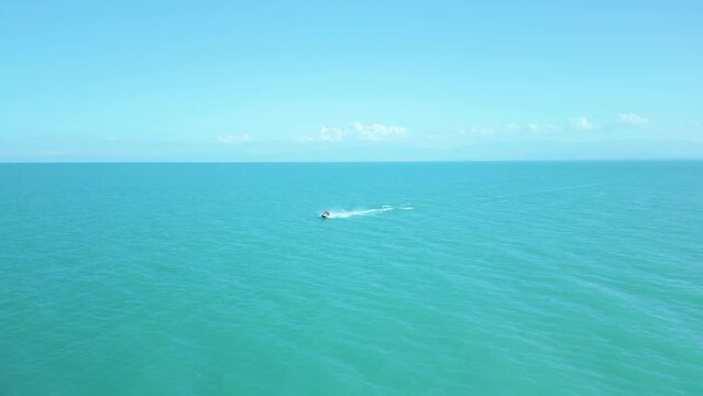 Aerial view of a man in a life jacket riding a jet ski on clear blue azure water on the sea. Sport, healthy lifestyle, outdoor recreation, vacation at sea, travel. Lake Sevan, Armenia.