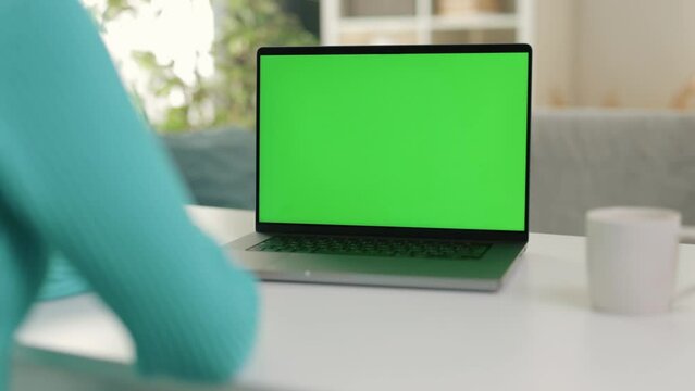 Close-up shot, woman using laptop, hands actively typing on keyboard as looks at computer screen, chroma key green screen