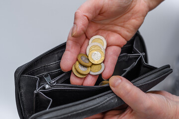 Kobieta wkłada polskie monety o nominałach 2zł 5zł do portfela