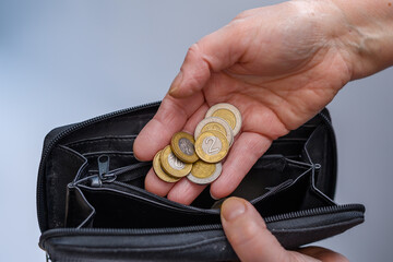 Polskie monety wkładane przez kobietę do portfela, bieda