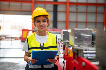 Portrait of female automation engineer standing in modern industrial factory and looking camera in industrial factory.