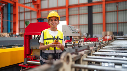 Portrait of female automation engineer standing in modern industrial factory and looking camera in industrial factory.