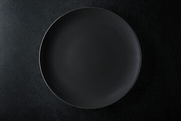 Empty black plate on a black stone table.