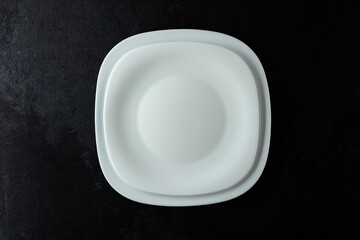 Empty white plates on a black stone table.