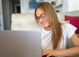 Happy young woman using laptop sitting at desk writing notes while watching webinar, studying online, looking at pc screen learning web classes or having virtual call meeting remote working from home