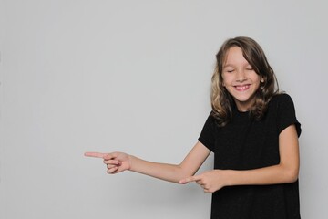 Girl smiles, points to the left, free space, white background