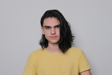 Portrait of serious young man, teenager with long black hair