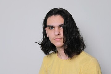 Portrait of handsome young man, teenager with long black hair, head shot