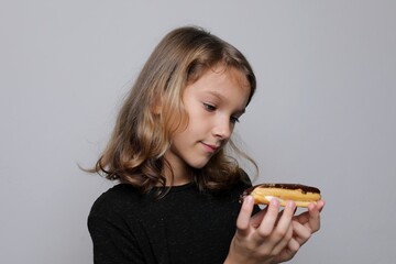 A junior schoolgirl girl holds a plate of dessert and doubts, looking sad