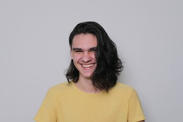 Portrait of laughing young man, teenager with long black hair