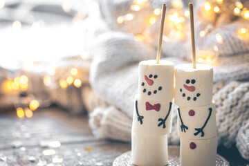 Cozy Christmas background with marshmallow snowmen and festive decor.