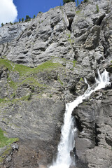Fototapeta na wymiar Mountain Waterfall in the Swiss Alps, Bottom Frame Right with Blue Sky in Upper Left Corner