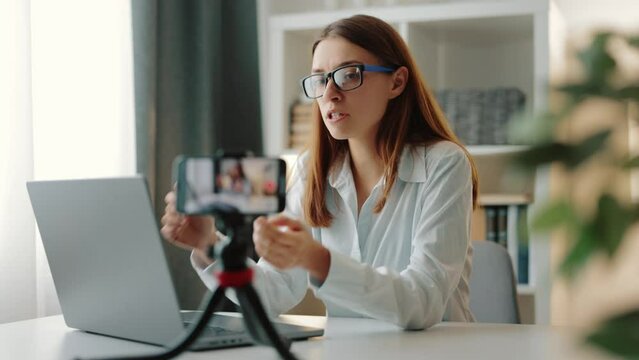 Close-up image on phone screen captures woman speaking to camera as actively records live tutorial vlog, similar to coach