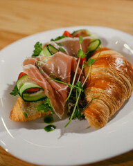 croissant sandwich with cherry tomatoes jamon and cucumber