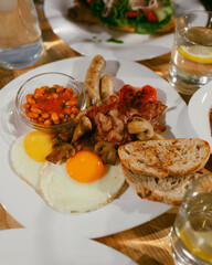 Full English breakfast on a plate with fried eggs, sausages, bacon, beans, toasts. Top view. Breakfast in restaurant