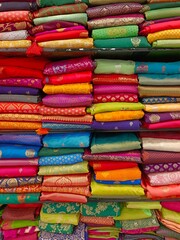 Neatly stacked colorful silk saris in racks in a textile shop, These exquisite, expensive sarees are famous for their gold and silver zari, brocade. Incredible India.