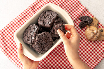 Woman holding tray with chocolate cookies, close up.