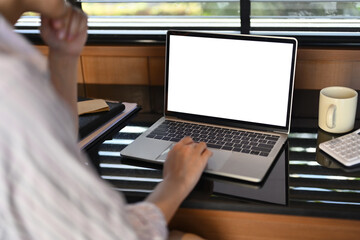 Cropped shot of young woman using laptop on black table near window