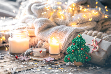 Cozy Christmas composition with gingerbread and candles on a blurred background.