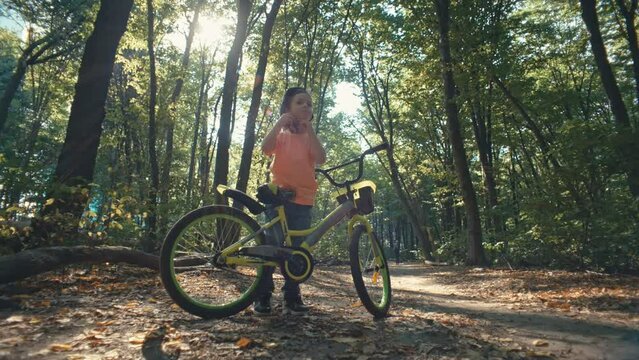 A child puts on a protective bicycle helmet and rides a bicycle in the park. Active, safe and protected recreation in nature for children. High quality 4k footage