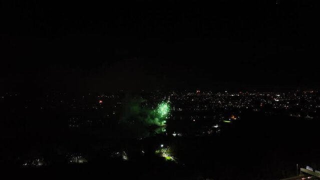 Aerial shot of large green fireworks exploding in the night sky at new years