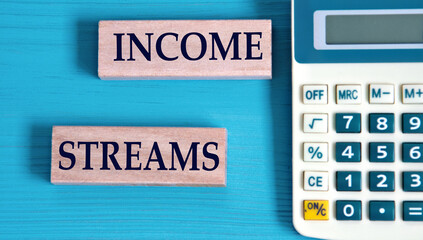 INCOME STREAMS- words on wooden blocks with a calculator in the background