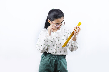 Young girl teaching. Portrait of Happy Indian teenage girl holding a yellow color wooden measuring ruler scale in hand and wearing specs. White background.