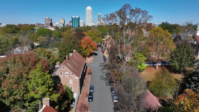 Old Salem in autumn. Aerial shot of historic district with colonial building contrasted by the tall Winston-Salem, North Carolina skyline.