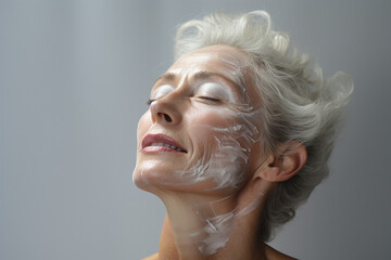 aged woman applying cream on her face