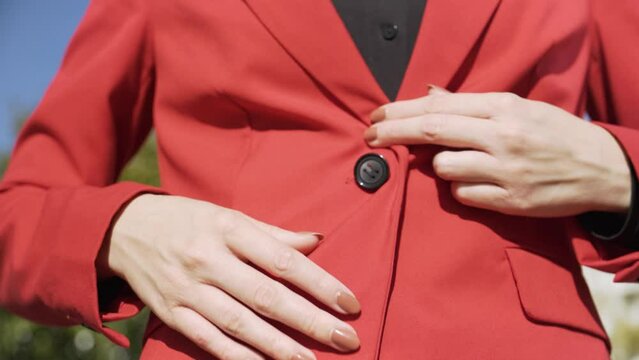 A businesswoman in a suit buttons up her jacket - closeup