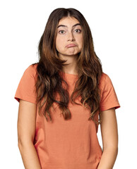 Young Caucasian woman in studio setting shrugs shoulders and open eyes confused.