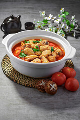 traditional chinese fried braised hot and spicy chilli tomato sauce chicken cutlet meat main course in hot soup clay pot on grey vintage background cafe hotel luxury halal food restaurant banquet menu