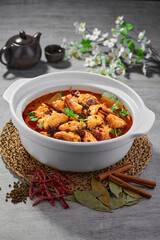 traditional chinese fried braised hot and spicy chilli tomato sauce chicken cutlet meat main course in hot soup clay pot on grey vintage background cafe hotel luxury halal food restaurant banquet menu