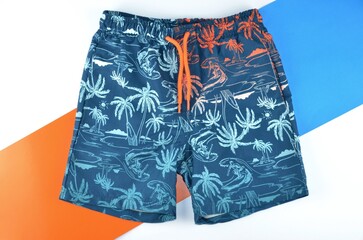 Beach shorts in dark blue, white and orange colors isolated on a background of the same colors