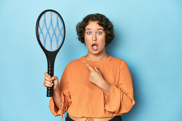 Young woman with electric mosquito racket Young woman with electric mosquito racketpointing to the...