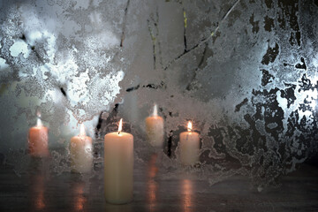 Five candles with warm light and frozen glass with dramatic illumination as a winter decoration for...