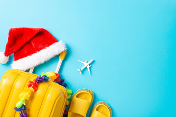 New Year, new tropical traditions! Overhead photo of suitcase, Santa hat, sandals, floral garland,...