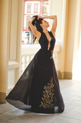 Girl in a long black dress is posing outside near the theater