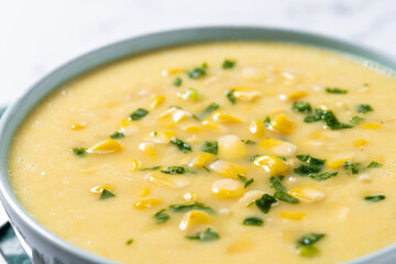 Corn soup in green bowl on white marble. Close up