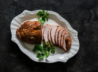 Delicious appetizer, tapas, snack - turkey pastrami on a white dish on a dark background, top view